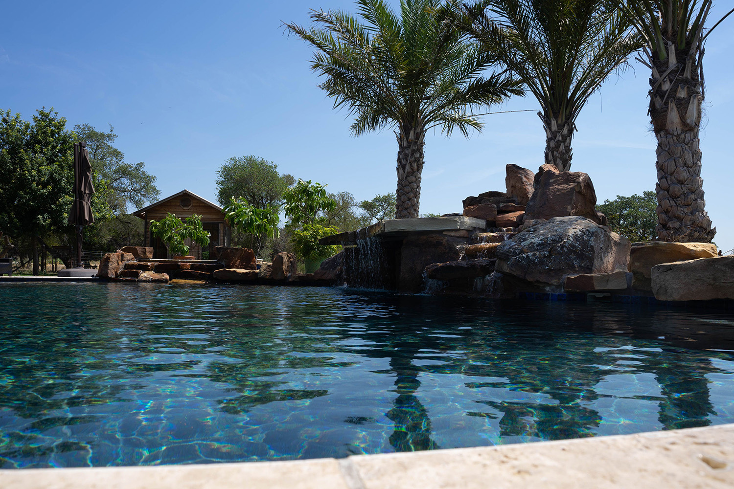 Poolscape with beautiful water features, accent boulders and rock waterfall